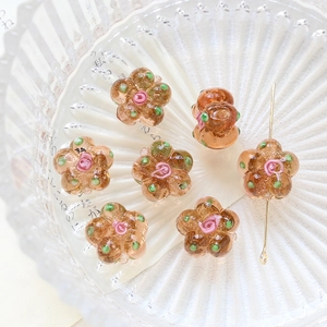 Detailed macro view of amber glass flower beads with pink rose accent for DIY jewelry