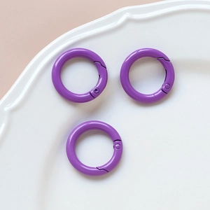 Close-up of three purple round spring gate rings on a white scalloped ceramic plate