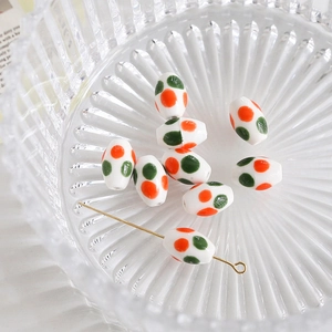 Detail of oval ceramic beads with orange and green polka dots for DIY jewelry making