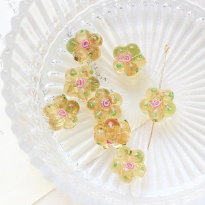 Macro shot of amber glass flower beads with pink rose details in a ribbed glass bowl