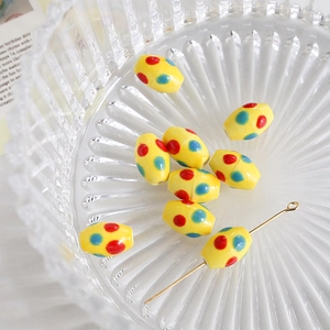 Detail of yellow oval ceramic beads with red and blue polka dots for DIY jewelry