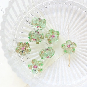 Macro shot of hand-painted translucent green glass flower beads with pink center for DIY jewelry