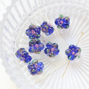 Macro shot of dark blue glass flower beads with gold powder and central drill hole