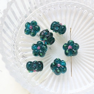 Detailed view of six hand-painted teal glass flower beads for DIY jewelry making