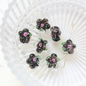 Macro detail of hand-painted floral glass beads with gold glitter and rose patterns