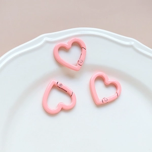 Macro detail of three pink heart-shaped metal carabiner clips for DIY keychains