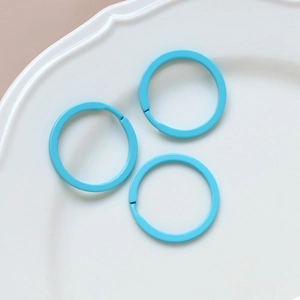 Three sky blue metal rings on a white ceramic tray for DIY jewelry making