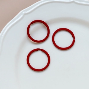 Three red macaron circle rings for DIY jewelry and keychains on a white ceramic plate