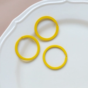 Detailed view of three bright yellow macaron heart keyrings on a white ceramic plate