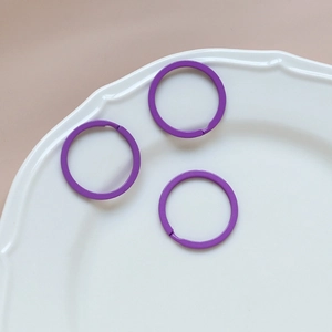 Three purple matte round keyrings in a white porcelain dish for DIY accessories