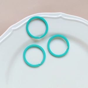 Detailed view of turquoise macaron-colored metal round rings in a white ceramic dish