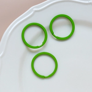 Three green macaron enamel metal keyrings for DIY jewelry on white ceramic tray