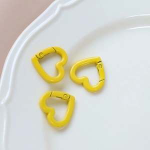 Close-up shot of three yellow heart-shaped metal lobster clasps for DIY jewelry crafts
