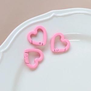 Close-up of three pink macaron heart-shaped metal spring rings on a white plate