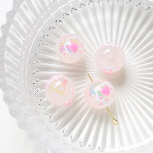 Macro shot of 4 pink translucent heart-patterned beads on a textured glass plate