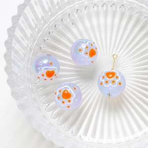 Close-up of iridescent purple beads with orange paw prints for DIY jewelry making