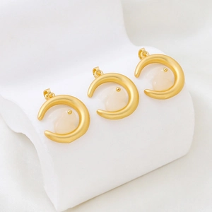 Macro detail of three gold-plated crescent moon and jade rabbit pendants with matte finish