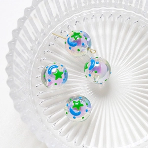Detailed view of iridescent star and moon beads in a glass bowl for DIY jewelry making