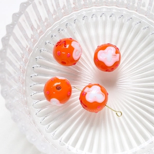Detail showing orange handmade floral beads with pink dots for DIY jewelry making
