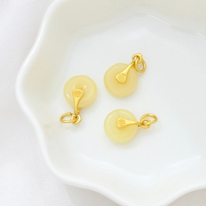Close-up of three jade-style gold-plated pendants on white silk for DIY jewelry making