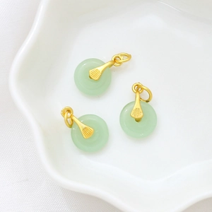 Detailed view of three light green jade pendants with golden ginkgo leaf clasps