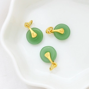Detail view of jade green donut charms with gold striped clasp in a white ceramic tray