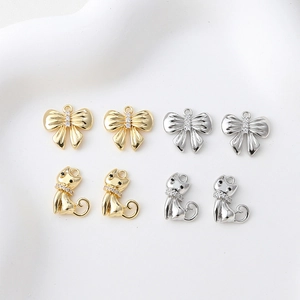 Makroansicht von Katzen- und Schleifenanhängern in Gold und Silber mit Zirkoniasteinen
