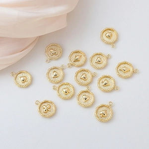 Detalle de dijes de póker bañados en oro de 18k con motivos de corazón, pica, trébol y diamante