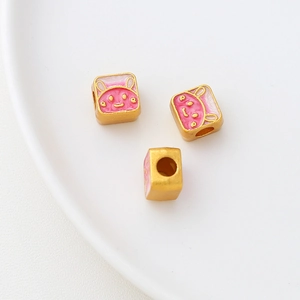 Macro shot of gold rabbit enamel square beads with pink and white details for DIY jewelry