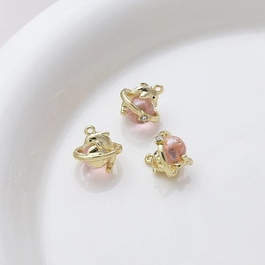 Detailed view of three golden dolphin alloy charms with pink beads on a white ceramic plate