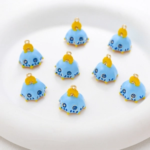 Close-up of blue enamel umbrella charms for DIY jewelry on a white ceramic plate