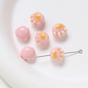 Détail macro de perles en céramique rose en forme de patte de chat pour bijoux artisanaux