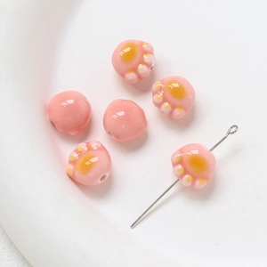 Détail macro de perles en céramique patte de chat rose et jaune pour bijoux DIY