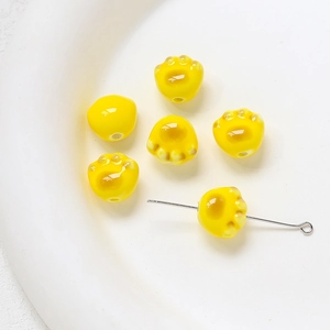 Détail de perles en céramique patte de chat jaune pour création de bijoux DIY