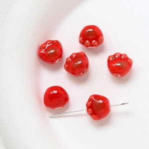 Vue macro de perles en céramique rouge en forme de patte de chat pour bijoux DIY