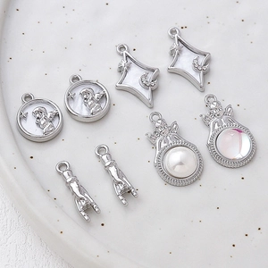 Silver alloy angel and star pendants for DIY jewelry making on white ceramic tray