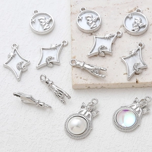Macro shot of silver angel pendants with pearl and moon details for jewelry making
