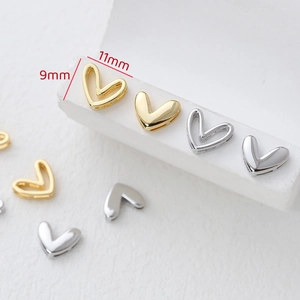 Macro shot of gold and silver heart-shaped jewelry charms for DIY necklaces, 9mm by 11mm size