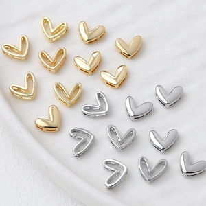 Polished 14k gold and silver heart charms for DIY jewelry making displayed on a tray