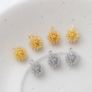 Exquisite 14k gold and silver starburst pendant charms on a ceramic plate for DIY jewelry
