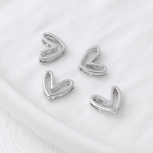 Macro detail of four silver heart-shaped hollow charms for DIY jewelry making