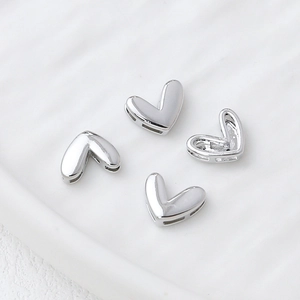 Macro detail of 14k gold-plated heart-shaped spacer beads with side holes for DIY jewelry
