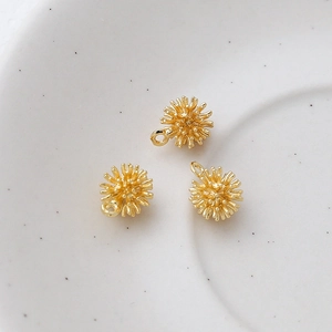Detailed macro view of three 14k gold-plated sea urchin charms for DIY jewelry making