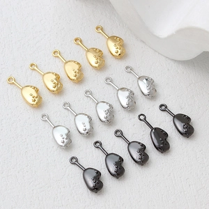 Close-up of irregular heart-shaped metal charms with star texture in gold, silver, and grey