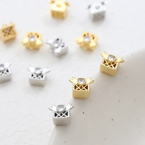 Macro detail of 14k gold plated square pendant with heart zircon and filigree mesh
