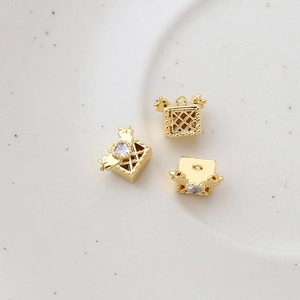 Macro shot of 14k gold-plated hollow cube jewelry charms with heart-shaped zircon stones