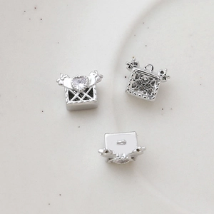 Macro detail of silver heart zircon box charms showing wing design and hollow back