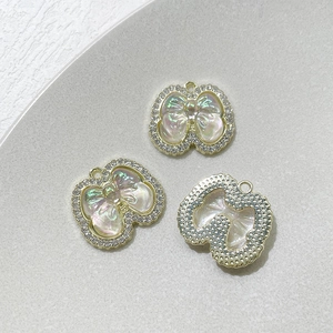 Vue détaillée de trois pendentifs papillon dorés sertis de zircons et finition aurore