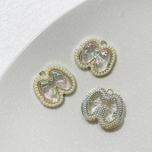 Détail macro de breloques nœuds en alliage avec résine irisée et perles pour bijoux DIY