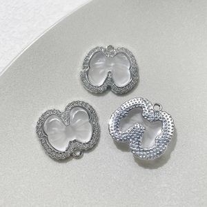 Vue détaillée de pendentifs nœuds argentés avec pierres blanches et strass pavés